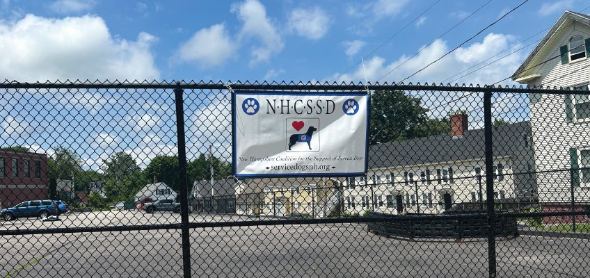 New Hampshire Coalition for the Support of Service Dogs banner hanging on a chainlink fence